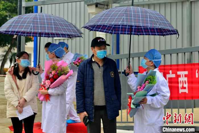 图为广西版“小汤山”医务人员送治愈患者离开。 李安祺 摄  广西版“小汤山”医院在院治疗近半数确诊患者治愈出院